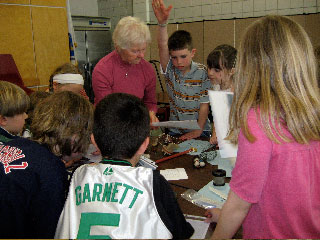 Rochester History
Rochester Historical Commission members presented a local history assembly to the 3rd grade a Rochester Memorial School. The presenters were, (top left)Fred Underhill displaying items from Stillwater Furnace, Henry Hartley showing pictures of local Native Americans, Cindy Underhill (spouse of RHC member) talking about the early cranberry industry, and Betty Beaulieu explaining about the early schools in Rochester and  Anna White showing artifacts from early churches, food and dress.

