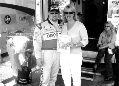 10-17-01
Wendy Ashworth of Rochester poses with a copy of The Wanderer alongside NASCAR racer Todd Bodine during a recent trip with husband and Rochester Fire Chief Scott Ashworth to Bodines Discover Card Winston Cup Team in Talladega, FL. Ms. Ashworth had the honor of cooking traditional New England scallops wrapped in bacon for the Number 26 team. Although Bodine finished 24th in the race due to a penalty in crossing the finish line, it was a trip to remember for the Ashworth family. 10/17/02 edition
