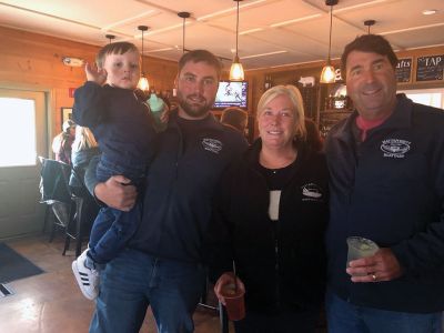 Mattapoisett Boatyard
From left, Ned Kaiser holds his son Hudson, while Jenn and David Kaiser join him for a photo during an October 7 event supporting Mattapoisett Boatyard employees. “Everyone was there! It was nice to see so many people, and the employees were surprised at the appreciation they were receiving,” said owner and General Manager David Kaiser. A $20 ticket to the charity event by Route 6 restaurant Rustico got attendees a meal and beverage with the Lions’ share (pun intended) going towards a $10,000 check donated 
