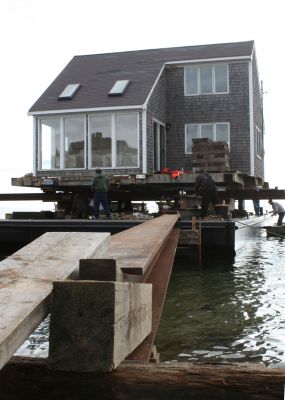 Hitting the Beach
A 25-ton house, gifted from Rochester resident Greg Kamon to soon-to-be Mattapoisett resident Deborah Francoeur, sits on a barge at the end of Brant Beach on November 5, 2009 while workers from New England Harbor Services and Mike Reid Mover Builders wait for 1:00 pm low tide to unload the house. Photo by Paul Lopes
