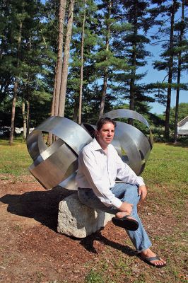 A Tribute to Heroes
Mattapoisett artist and sculptor Keith Francis poses with the sculpture he designed and built in tribute to the Worcester Six, the firefighters who perished in the tragic Worcester Warehouse fire on December 3, 1999. The massive one-ton sculpture now sits in his North Street backyard in clear view of several neighbors who are either firefighters, retired firefighters or relatives of firefighters. (Photo by Robert Chiarito).
