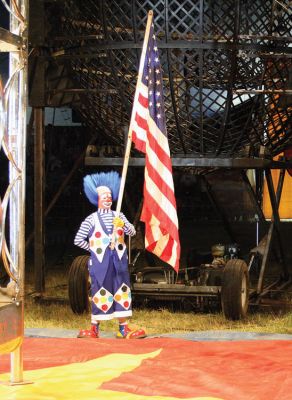 Flying Colors
A clown performer from Cole Brothers Circus of the Stars salutes the Stars and Stripes at the beginning of one of the four performances held recently in Rochester on June 25 and 26 under the Big Top pitched in the field adjacent to the Plumb Corner Mall. (Photo by Robert Chiarito).
