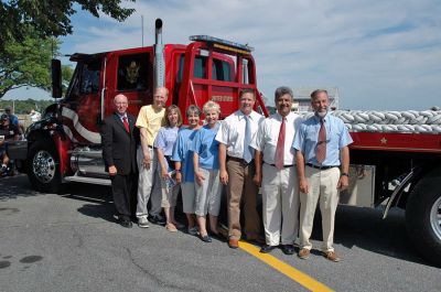 Glory Unfurled
Members of the Mattapoisett 150th Committee and the Board of Selectmen pose alongside the National Flag Truck exhibit which provided the large American flags which were unfurled in the area of the Town Wharf and Shipyard Park on Sunday afternoon, August 12. (Photo by Tim Smith).
