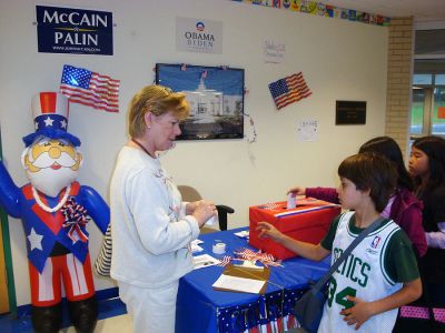 Mock Election
The Sippican School Student Council (Grades 4-6) held a mock presidential election last week, as did many schools across the country just a week prior to the national election. Here teacher Diane Cook directs student Alexei Sudofsky after voting while students Alissya Silva and Ayana Hartley line up behind to cast their own ballots. The Democratic ticket of Obama/Biden won with a majority 56 percent of the vote (239), while the Republican ticket of McCain/Palin garnered only 42 percent (180 votes).

