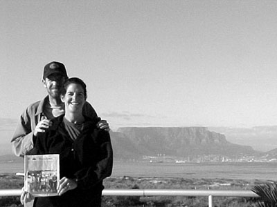 01-31-02-1
Dan and Lisa Winsor of Mattapoisett recently returned from an extended trip to South Africa and here they are posing with a copy of The Wanderer in Table View, South Africa. In the background is the city of Cape Town and Table Mountain.  (Photo courtesy of Dan and Lisa Winsor). 1/31/02 edition
