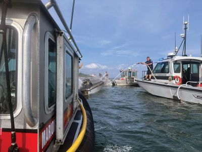 Boat Fire
All passengers escaped without harm after a small boat in Aucoot Cove was swallowed up in flames on July 1. Marion M225 responded to the boat fire, and activation of the Buzzards Bay Task Force followed. Marion Assistant Harbormaster David Wilson can be seen dousing the flames with assistance from the Mattapoisett, New Bedford and Wareham fire departments, Mattapoisett Harbormaster and New Bedford Police. Photos courtesy Marion Fire Department
