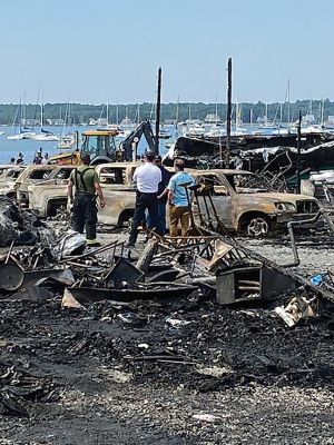 Mattapoisett Boatyard Fire
Smoke rose over Mattapoisett Harbor on August 19 after a boat caught fire during the replacement of a gasoline tank. An explosion followed by a raging fire leveled Mattapoisett Boatyard and destroyed the 14 boats and 47 vehicles on site. Members of the Kaiser family who own the business and members of the McLean family who founded the business surveyed the ruins on the weekend and vow to rebuild. Photos by Marilou Newell and courtesy of Mattapoisett Police and Fire departments and Kathleen Costello
