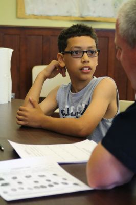 CSI Chemistry
During the CSI Chemistry event at the Mattapoisett Free Library on August 1, Rochester Police Chief Paul Magee fingerprinted the kids during a fingerprinting demonstration, and Brendan Taylor, age 10, was the first one up. Chief Magee’s son Rob Magee led the presentation, which was one of the library’s exciting children’s summer events. Photo by Jean Perry
