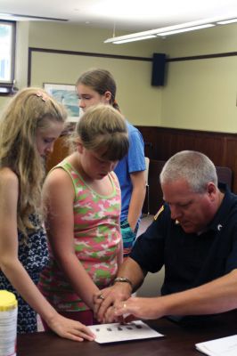 CSI Chemistry
During the CSI Chemistry event at the Mattapoisett Free Library on August 1, Rochester Police Chief Paul Magee fingerprinted the kids during a fingerprinting demonstration, and Brendan Taylor, age 10, was the first one up. Chief Magee’s son Rob Magee led the presentation, which was one of the library’s exciting children’s summer events. Photo by Jean Perry
