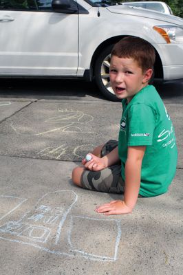 Chalk It Up
The day before the Marion Town Party, kids chalked-up the sidewalks in front of the Marion Town House in preparation for the Saturday night event. Town Party Planning Committee members set up picnic tables and strung party lights in the background while the kids drew colorful, festive pictures with chalk. Photos by Jean Perry
