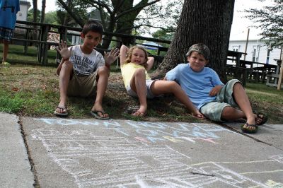 Chalk It Up
The day before the Marion Town Party, kids chalked-up the sidewalks in front of the Marion Town House in preparation for the Saturday night event. Town Party Planning Committee members set up picnic tables and strung party lights in the background while the kids drew colorful, festive pictures with chalk. Photos by Jean Perry
