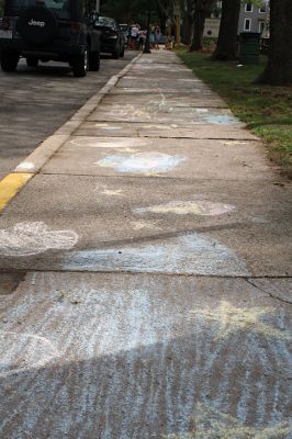 Chalk It Up
The day before the Marion Town Party, kids chalked-up the sidewalks in front of the Marion Town House in preparation for the Saturday night event. Town Party Planning Committee members set up picnic tables and strung party lights in the background while the kids drew colorful, festive pictures with chalk. Photos by Jean Perry
