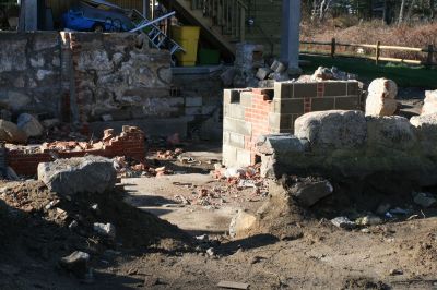 Historic Fire
The Dexters are trying to salvage the granite from the original foundation of the 1690 house. Bricks from a chimney are scattered at the old foundation. Susan Dexter used a metal detector to find artifacts from the site, and turned up an Indian-head penny and a couple heavily rusted items.
