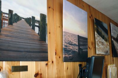 Mattapoisett Harbormaster
Mattapoisett Harbormaster Jill Simmons has become a de facto art museum curator since the town acquired prints and photographs that now grace the walls of the tiny harbormaster’s office at Shipyard Park. Local photographer Misty King has several of her pieces on display, along with two pieces by USCG’s artist Michael Mazur. Mazur’s pieces depict scenes from the 2003 Bouchard oil spill off West Island. Simmons welcomes the public to stop by and take a look at the mini art installation. Photo by Marilou Newel
