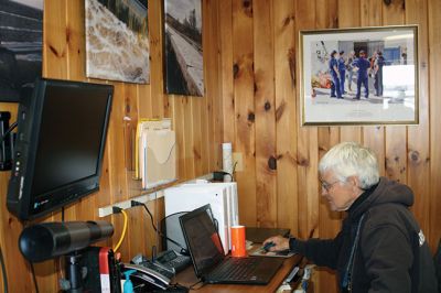 Mattapoisett Harbormaster
Mattapoisett Harbormaster Jill Simmons has become a de facto art museum curator since the town acquired prints and photographs that now grace the walls of the tiny harbormaster’s office at Shipyard Park. Local photographer Misty King has several of her pieces on display, along with two pieces by USCG’s artist Michael Mazur. Mazur’s pieces depict scenes from the 2003 Bouchard oil spill off West Island. Simmons welcomes the public to stop by and take a look at the mini art installation. Photo by Marilou Newel
