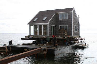 Hitting the Beach
A 25-ton house, gifted from Rochester resident Greg Kamon to soon-to-be Mattapoisett resident Deborah Francoeur, sits on a barge at the end of Brant Beach on November 5, 2009 while workers from New England Harbor Services and Mike Reid Mover Builders wait for 1:00 pm low tide to unload the house. Photo by Paul Lopes
