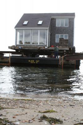 Hitting the Beach
A 25-ton house, gifted from Rochester resident Greg Kamon to soon-to-be Mattapoisett resident Deborah Francoeur, sits on a barge at the end of Brant Beach on November 5, 2009 while workers from New England Harbor Services and Mike Reid Mover Builders wait for 1:00 pm low tide to unload the house. Photo by Paul Lopes
