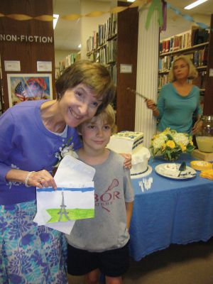 Judy Kleven Retires
Scores of admirers gathered on Friday to celebrate the service of Head Librarian Judy Kleven, who retired after 27 years at Elizabeth Taber. Young Max Richins presented Kleven with an Eiffel Tower-themed card, as she hopes to travel to Paris in retirement, while others brought a book-shaped cake and a new cat – Noah. Photos by Joan Hartnett-Barry
