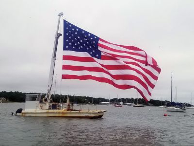 4th of July
Mattapoisett Boatyard set up its 40-foot mooring barge with a 50-foot crane to display a 30 foot by 50 foot American flag in the middle of Mattapoisett harbor. The flag was supplied by Richard DeMello, who owns Bete-Fleming Inc. in Mattapoisett and was reportedly thrilled to see the flag on display. Ned Kaiser of Mattapoisett Boatyard conjured up the idea a few days prior, thinking this would be a great way to give back and display the United States flag boldly and with pride. Photo courtesy David Kaiser
