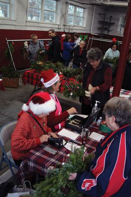 Mattapoisett Woman’s Club
Sandra Hering is decked out in Santa attire as she invites traffic to turn into Saturday morning’s sale of wreaths and other assorted Christmas decorations at the Fire Station on the corner of Route 6 and Barstow in Mattapoisett. The annual event, put on by the Mattapoisett Woman’s Club, raises money to fund a college scholarship. Photos by Mick Colageo
