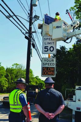 On the ‘Clock’ 
Now you can literally watch your speed as you (hopefully) watch your speed on Route 6 with the two new permanent traffic speed indicators both east and west of the Little Neck Village entrance in East Marion. Rep. William Straus joined Police Chief John Garcia, MassDOT workers, and the Board of Selectmen early on Tuesday, June 12, for the unveiling and installation of the signs. Seen here, a State Trooper chats while Chief Garcia watches the sign flash a prompt to drivers who exceed 60 mph. Photo Jean Perry
