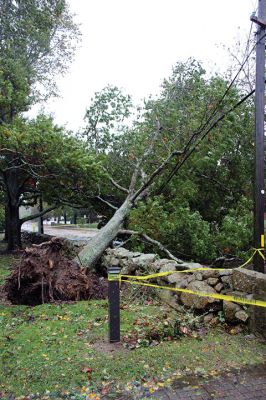 Storm Damage
An uprooted tree lays across the front lawn of a ranch house on Front Street near Silvershell Beach in Marion last Friday. Earlier in the day, a Mattapoisett Fire truck monitored the scene after a downed powerline caused a fire and closed Water Street down the street from Town Hall. North of Route 195 in Mattapoisett, a snapped-off tree is held up by a utility wire. Photos by Mick Colageo and Marilou Newell. November 4, 2021 edition
