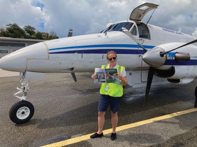 San Juan, Puerto Rico
Kate Fredericks, originally from Mattapoisett, currently lives in San Juan, Puerto Rico. She is an airline pilot flying for Ameriflight, and flies UPS and DHL cargo from Puerto Rico to the Caribbean islands. Seen here, Fredericks waits for her outbound cargo in St. Martin, Netherlands Antilles, reading a copy of The Wanderer!
