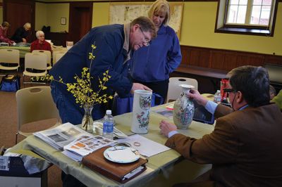 Library Treasures
Word spread of the Antiques Roadshow-style fundraiser at the Mattapoisett Library on March 29, attracting scores of South Coasters clutching their treasures, antiques, and heirlooms for appraisal and admiration, hoping Francis McNamee of the Marion Antique Shop might discover worth in their belongings beyond their sentimental value. Paying $5 per item appraised, some brought primitive dolls, old books, tea sets, and artwork. By Jean Perry
