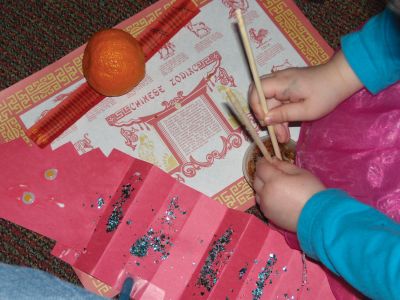 Chinese Culture
Children learned about Chinese culture and the Year of the Rabbit at a February 24, 2011 Mattapoisett library event. Librarian Linda Burke read a traditional Chinese story, and then the children enjoyed making their own dragons, watched as Haiying Zhang wrote their names in Mandarin, and tried eating fried rice with chopsticks. Photo by Anne Kakley.
