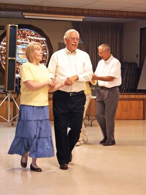 Squaring Off
The Reverend Robert Macfarlane of the First Congregational Church in Marion steps it up with his partner during the first of what promises to be a series of annual Square Dances held on Sunday, September 14. Originally planned to be held in the parking area adjacent to the Marion General Store, the inclement weather forced the venue indoors to the nearby Community Center. (Photo by Robert Chiarito).
