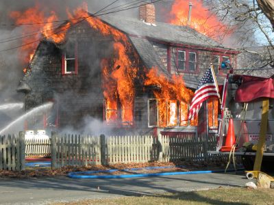 Fatal Fire
A devastating house fire at 13 Briar Road in the Point Connett area of Mattapoisett claimed the life of the sole occupant, 72-year-old Carlton Cook, on Sunday afternoon, February 3. Fire officials were concerned with two liquid propane tanks near the building which can be seen here in the left foreground. (Photo by Paul Lopes).
