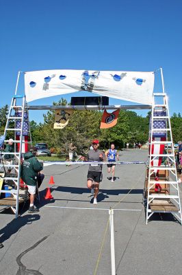 Marion Village 5K
Nephi Tyler of Fairhaven (front) crosses the finish line to take the top overall honors in the tenth annual Marion Village 5K Road Race. Mr. Tyler narrowly beat out second-place winner Sean Livingston of Barrington, RI (back) who crossed the finish line barely a second after the winning time of 15:48. (Photo by Robert Chiarito).
