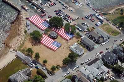 Glory Unfurled
Mattapoisett's weeklong 150th Sesquicentennial Celebration was capped off with a closing ceremony featuring the glorious unfurling of three large versions of the Stars and Stripes, courtesy of the National Flag Truck exhibit, in the area of the Town Wharf and Shipyard Park on Sunday afternoon, August 12. (Photo by Ken Howland).
