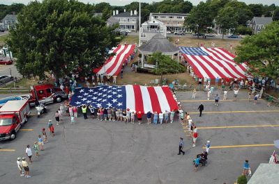 Glory Unfurled
Mattapoisett's weeklong 150th Sesquicentennial Celebration was capped off with a closing ceremony featuring the glorious unfurling of three large versions of the Stars and Stripes, courtesy of the National Flag Truck exhibit, in the area of the Town Wharf and Shipyard Park on Sunday afternoon, August 12. (Photo by Tim Smith).
