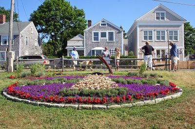 Garden Glory
Members of Mattapoisetts 150th Garden Group recently posed for this aerial shot of the sesquicentennial logo they recreated out of plantings at Shipyard Park. The group members have put in countless hours planting this and other beds from Shipyard Park to Neds Point to commemorate the towns 150th birthday. This photo is also being planned as the cover for the next Annual Town Report. (Photo by Robert Chiarito).
