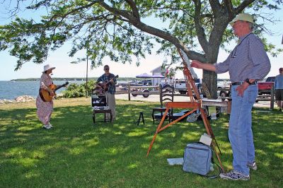 Arts in the Park
Marion artist Charles Parsons paints a portrait while Mattapoisett Library Director and musician Judy Wallace and her husband David Gries perform during the recent "Arts in the Park" benefit to raise money for furnishings in the new Mattapoisett Public Library which was held on Sunday, June 24 in Shipyard Park in Mattapoisett. (Photo by Robert Chiarito).
