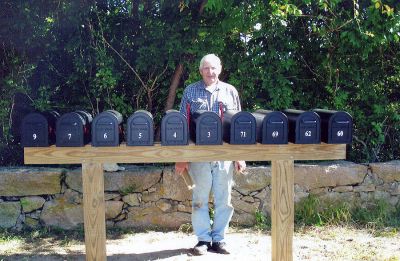 Mail Man
Bernard Talty of Mattapoisett poses behind the new mailboxes that have been installed on the corner of North Street and Edgewood Lane that he helped design. The new mailboxes have eliminated the blind spots caused by the prior mailboxes so those pulling out of Edgewood can now safety exit onto North Street. The new mailboxes were installed as part of a neighborhood effort with assistance from the Mattapoisett Highway Department and local Post Office. (Photo courtesy of Ann Lynch).
