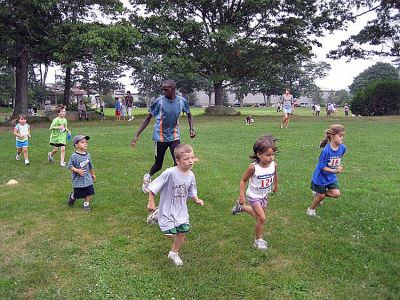 Running Man
Kenyan runner Nicholas Kamakya trains with kids during the final Marion Mile Just for Kids competition held last week at Tabor Academy. The athlete talked about running in Kenya and led the kids through warm-ups and stretching prior to jogging along in the back of the pack with some of the youngest competitors. (Photo courtesy of Chris Adams).
