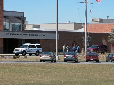 ORR Bomb Scare
Mattapoisett Police and Fire officials wait outside the main entrance of Old Rochester Regional High School during a bomb threat which forced the evacuation of the school on Monday morning, April 9. Students were bused to Tabor Academy in nearby Marion while the threat was investigated. (Photo by Kenneth J. Souza).
