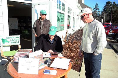 Sippican Signing
Author and Sippican Lands Trust (SLT) member Peter C. Stone recently signed copies of his book, The Untouchable Tree, as a benefit for the SLT at their offices in the Pilgrim Bank Plaza at 354 Front Street in Marion. The book, which is about our connection to the magnificence and essential nature of trees, is 192 pages and is illustrated with 30 color paintings. Here Mr. Stone is seen signing a book for customer Brent Burrell (right) while SLT member Allan Ditchfield looks on. (Photo by Robert Chiarito).
