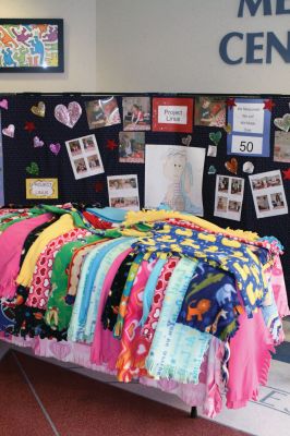 Project Linus
Fifteen students from Jane Tougas' eighth grade Enrichment Class display the 50 blankets they helped make for Project Linus, a charity that provides handmade blankets to seriously ill and traumatized children. Front row, left to right: Olivia Lanagan, Lizzie Machado, Seth Richard, and Chris Demers. Back row, left to right: Renae Reints, Tori Saltmarsh, Katie Zartman, Kelly Kay, Ali Grace, Nicholas Bergstein, and Andrew Dessert. Photo by Anne O'Brien-Kakley.
