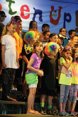 Lighten Up
Third-graders on June 16 performed their play “Lighten Up,” donning rainbow wigs, gigantic glasses, tutus, and brightly colored mustaches to remind everyone to not take themselves so seriously all the time. The students sang silly songs, told jokes, and offered some valuable advice like, “When life makes you sweat, wear deodorant!” By Jean Perry

